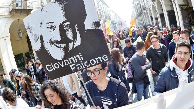 Des manifestants défilent à Turin, le 21 mars 2016, avec une pancarte en souvenir du juge Falcone, assassiné par la mafia. En Italie, le premier jour du printemps est dédié à la lutte contre le crime organisé. [Keystone - Alessandro Di Marco]