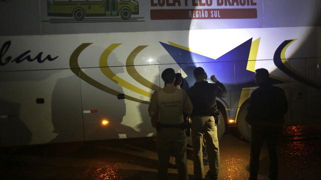 Des policiers inspectent la caravane électorale de Lula après qu'un bus a été visé par des tirs. [Keystone - Eraldo Peres]