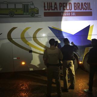 Des policiers inspectent la caravane électorale de Lula après qu'un bus a été visé par des tirs. [Keystone - Eraldo Peres]