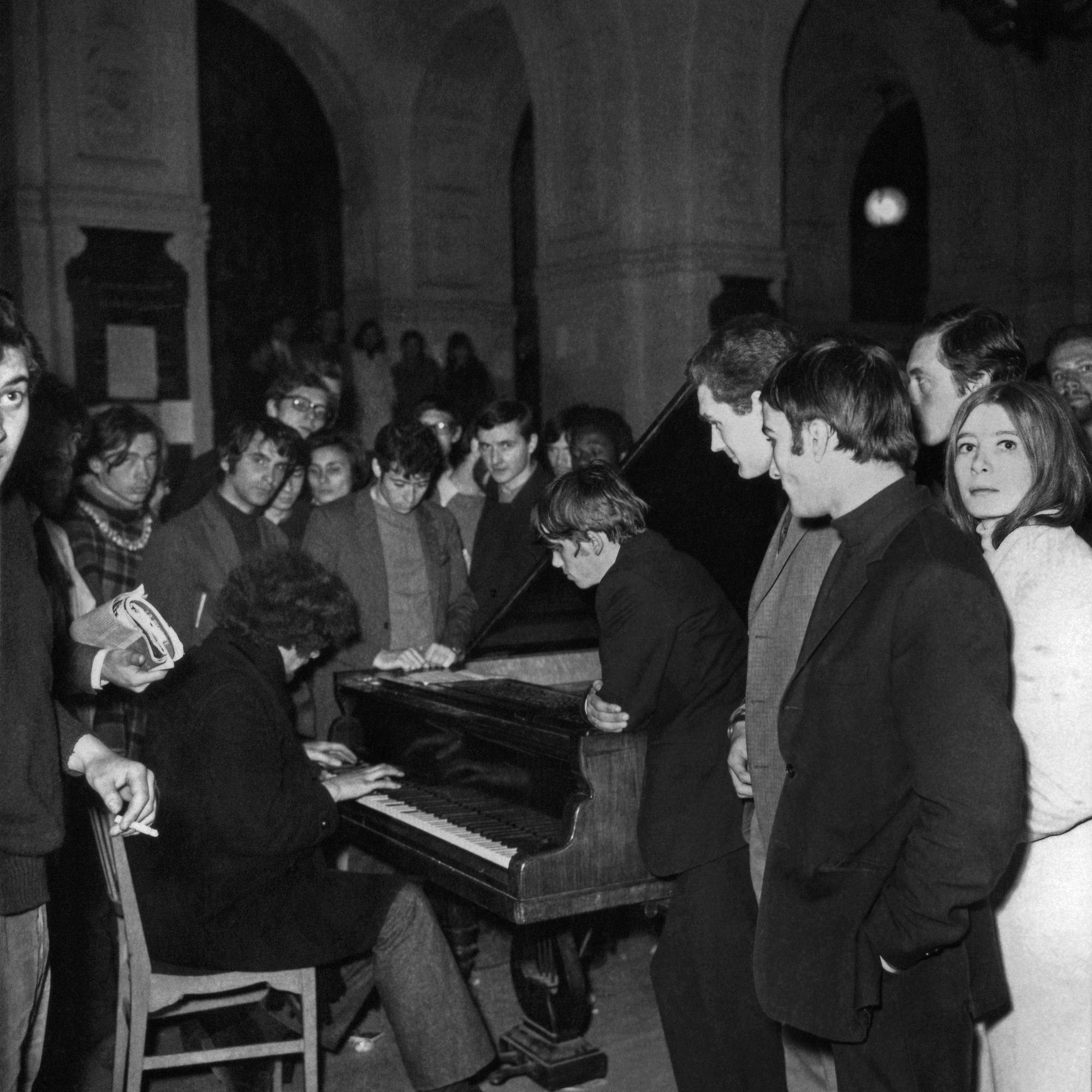Un jeune homme joue du piano au milieu d'étudiants à l'université de la Sorbonne, à Paris, le 20 mai 1968. [AFP - Archives]