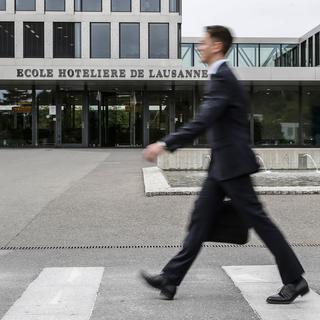 Un étudiant passe devant l'entrée de l'Ecole Hôtelière de Lausanne (EHL). [Keystone - Peter Klaunzer]