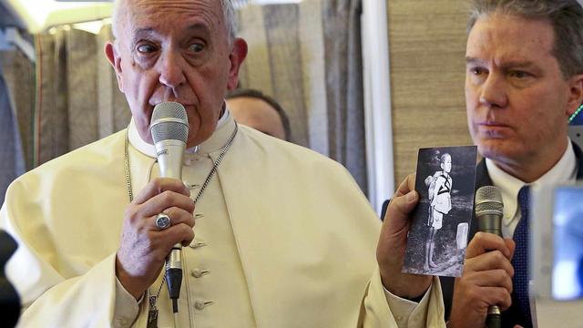 Le pape François dans l'avion qui l'emmenait au Chili, tenant une photo montrant une victime de Nagasaki. [Keystone/EPA - Alessandro Bianchi]