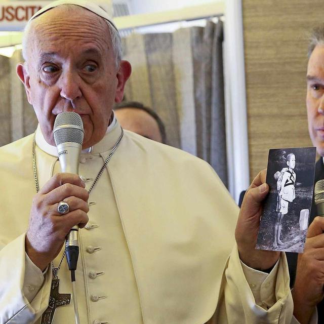 Le pape François dans l'avion qui l'emmenait au Chili, tenant une photo montrant une victime de Nagasaki. [Keystone/EPA - Alessandro Bianchi]