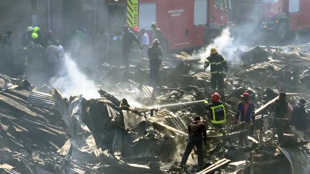 Pompiers et secouristes s'activent sur les lieux d'un incendie qui a dévasté un marché à Nairobi, au Kenya, jeudi 28 juin. [Keystone - AP Photo]