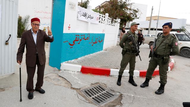 Un homme lève son doigt taché d'encre après avoir voté à un bureau de vote pour l'élection municipale de Tunis. [Reuters - Zoubeir Souissi]