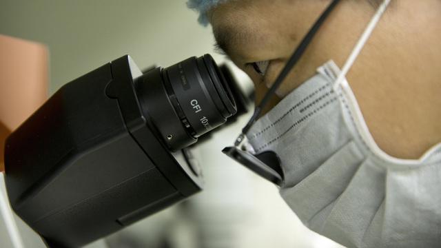 Un scientifique chinois regarde dans un microscope dans un laboratoire à Shenzhen. [AP/Keystone - Mark Schiefelbein]