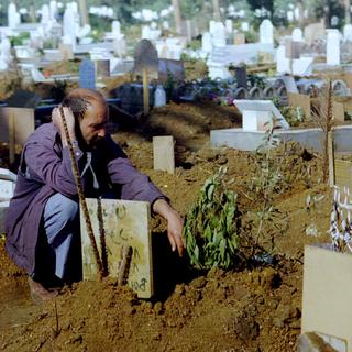 Un homme sur la tombe de son fils, tué lors des années noires (image d'archive). [Reuters - PBEAHUMZUET]