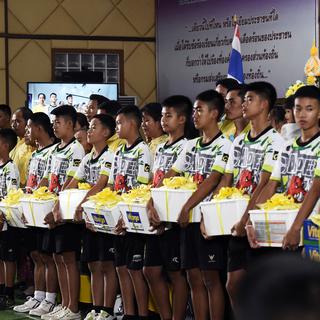 Les douze enfants et leur entraîneur de football sauvés d'une grotte en Thaïlande en bonne forme devant la presse. [AFP - Lillian Suwanraupha]