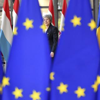 Brexit: la Première ministre britannique Theresa May cachée derrière le drapeau européen. [Keystone - AP Photo/Geert Vanden Wijngaert]