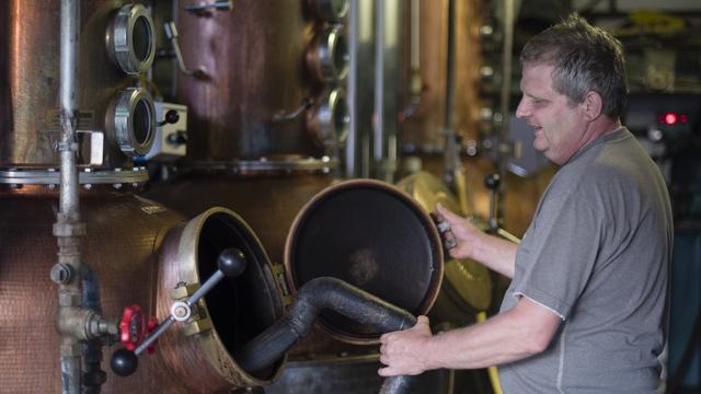 Frédéric Schneider en train de travailler dans sa distillerie de Cornol (ici en juillet 2015). [Keystone - Stefan Meyer]