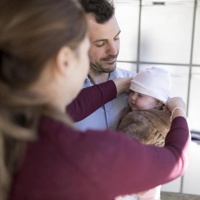 Un père et une mère s'occupent de leur bébé de cinq mois. [Keystone - Gaëtan Bally]