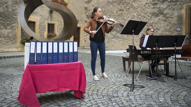 Deux élèves de la Haute école de musique de Neuchâtel et les classeurs contenant les signatures de l'initiative. [Keystone - Laurent Gillieron]