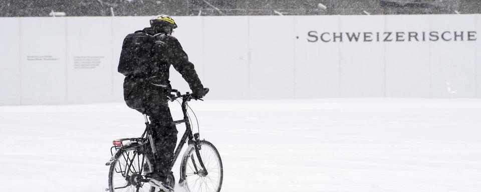 Un cycliste traverse la Place fédérale à Berne ce 1er mars. [Keystone - Anthony Anex]