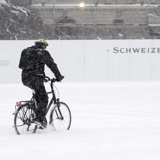 Un cycliste traverse la Place fédérale à Berne ce 1er mars. [Keystone - Anthony Anex]