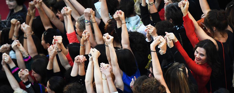 Des réalisatrices, des comédiennes et productrices se tiennent la main sur le tapis rouge de Cannes pour protester contre le peu de femmes primées sur la Croisette. [AFP - Anne-Christine Poujoulat]