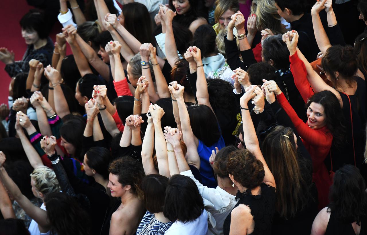 Des réalisatrices, des comédiennes et productrices se tiennent la main sur le tapis rouge de Cannes pour protester contre le peu de femmes primées sur la Croisette. [AFP - Anne-Christine Poujoulat]