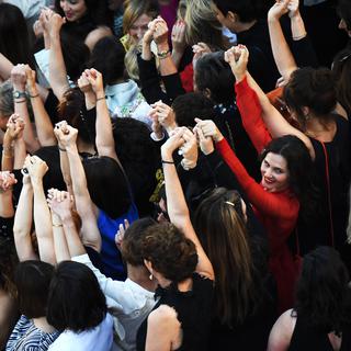 Des réalisatrices, des comédiennes et productrices se tiennent la main sur le tapis rouge de Cannes pour protester contre le peu de femmes primées sur la Croisette. [AFP - Anne-Christine Poujoulat]
