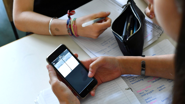 Dans tous les cantons romands, les élèves doivent garder leur portable éteint et "invisible". [ZB/DPA/AFP - Jens Kalaene]