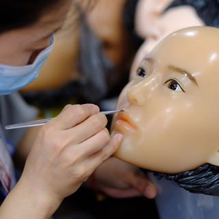 Une maquilleuse personnalise le visage d'une poupée selon la demande du client. [RTS - Michael Peuker]