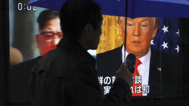 Sur un écran tv, le leader nord-coréen Kim Jong-un et le président des Etats-Unis Donald Trump. [Keystone - Eugene Hoshiko]