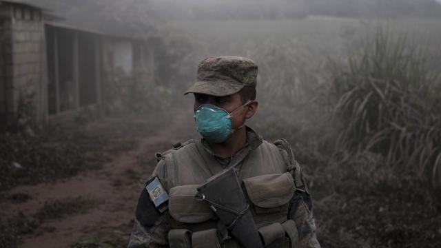 Un soldat se tient sur un site parcouru par les secours après l'éruption du "Volcan de feu". [AP/Keystone - Oliver de Ros]