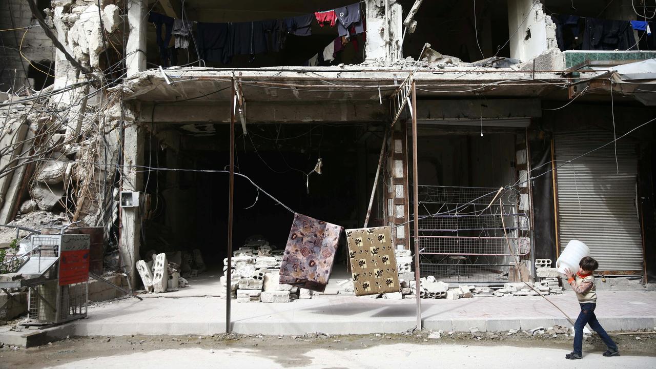 Un jeune garçon passe devant un immeuble éventré à la suite de bombardements. [Reuters - Bassam Khabieh]