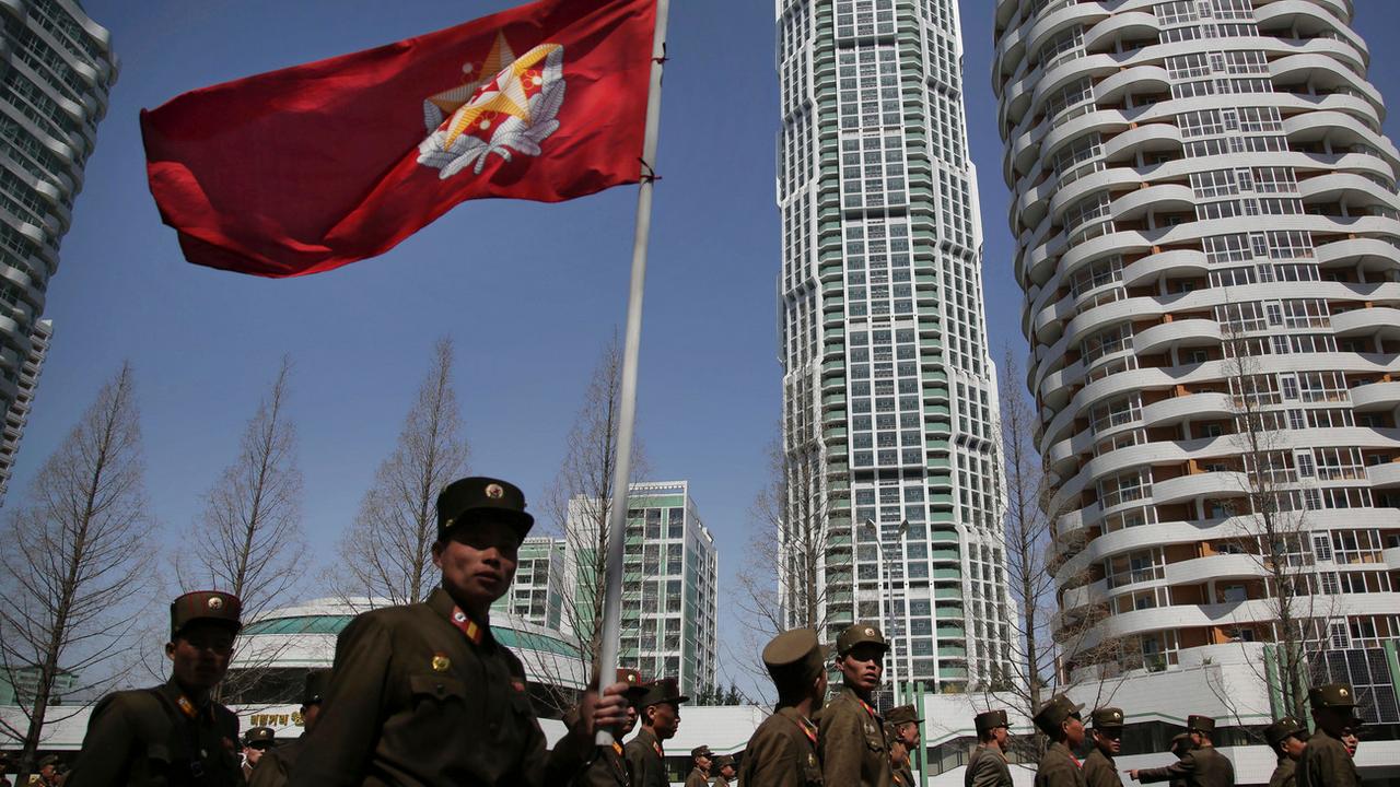 Soldats nord-coréens portant le drapeau de l'Armée populaire, dans un quartier résidentiel de Pyongyang. [Keystone - Wong Maye-E]