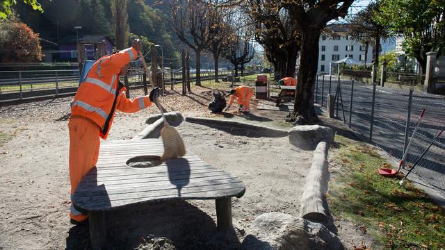 Des requérants d'asile lors de l'entretien d'un parc à Biasca, au Tessin (image d'illustration). [Keystone - Francesca Agosta]