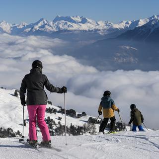 Des skieurs sur une piste du domaine skiable de Crans-Montana. [Keystone - Jean-Christophe Bott]