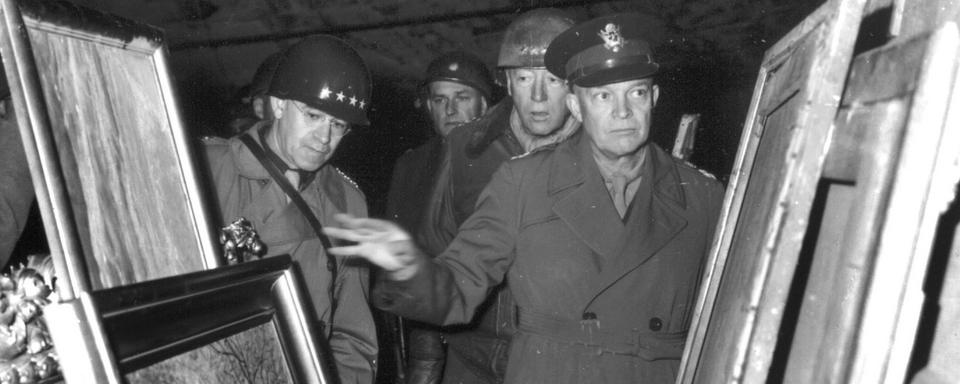 Le général Eisenhower examine le 12 avril 1945 des oeuvres d'art volées par le gouvernement nazi dans les pays occupés et cachés dans une mine de sel en Allemagne. [Keystone]