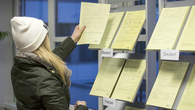 Une jeune femme regarde des formulaires dans un office de placement (image d'illustration). [Keystone - Peter Klaunzer]