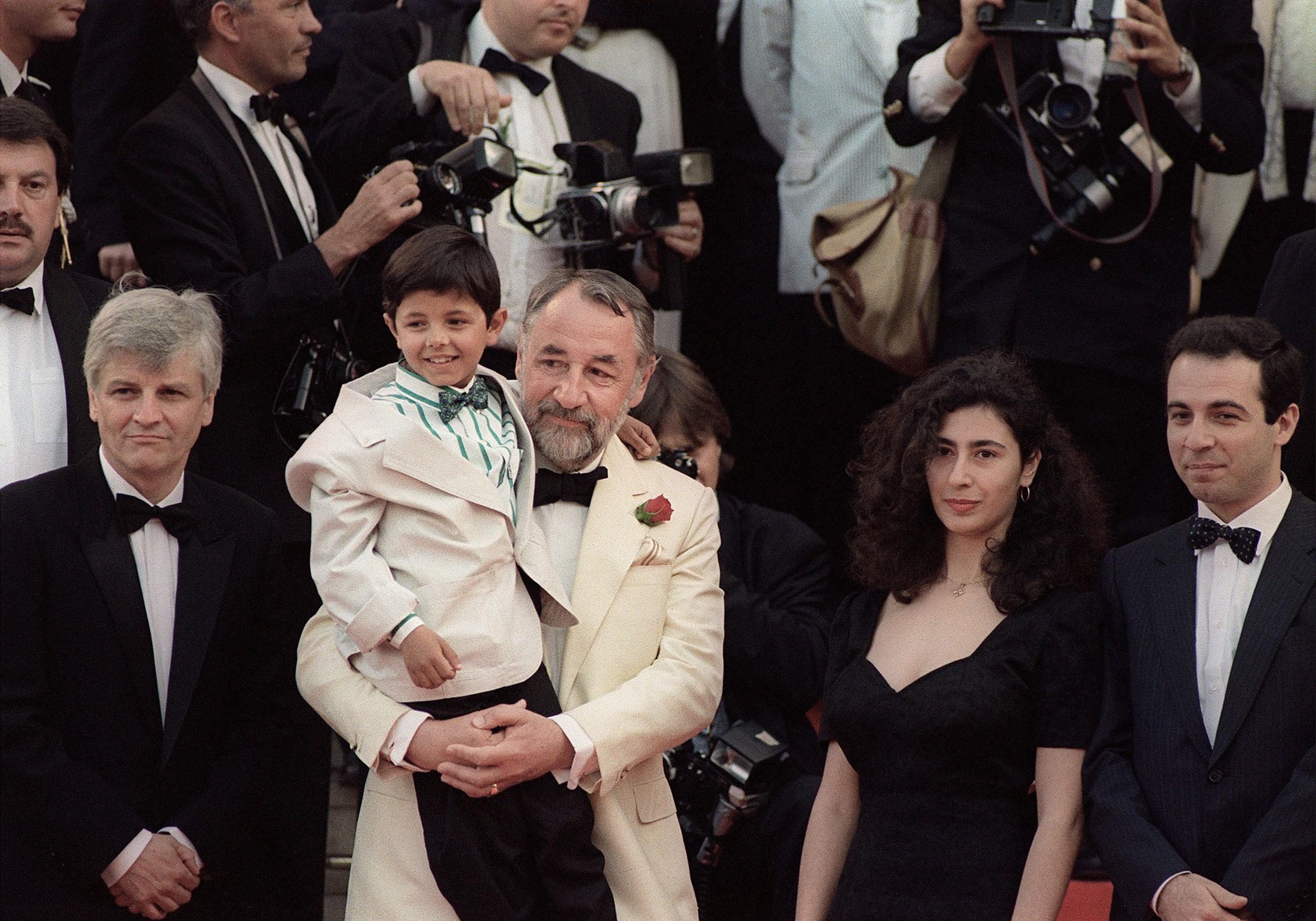 L'acteur français Philippe Noiret tient dans ses bras le petit acteur italien Salvatore Cascio, le 21 mai 1989 à Cannes, lors de la présentation du film "Cinéma Paradiso". [STF/AFP]