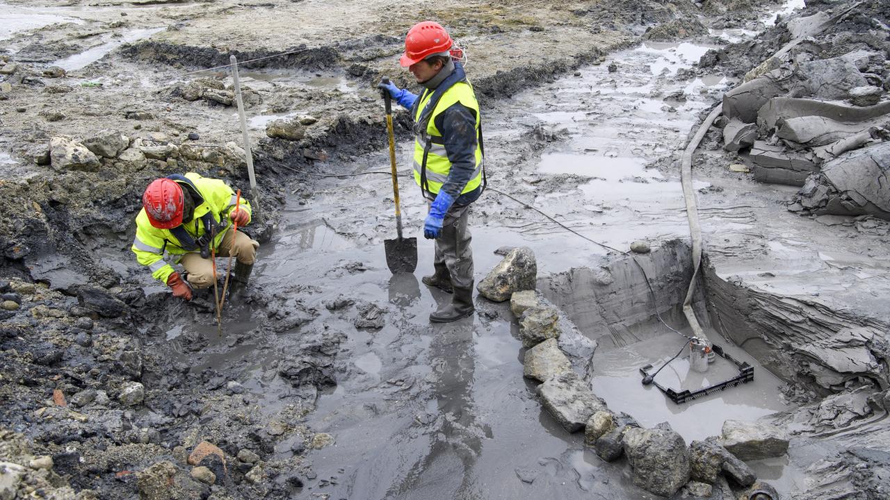 Des archéologues travaillent à dégager un pieu pris dans l'argile aux Eaux-Vives à Genève, sur un site palafittique datant de 2600 ans avant J.-C. [Keystone - Martial Trezzini]