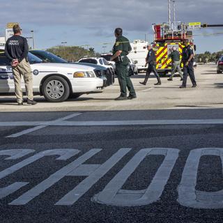 Des policiers se tiennent près de l'entrée du lycée Marjory Stoneman en Floride, cible d'une tuerie qui a fait 17 morts le 14 février 2018.