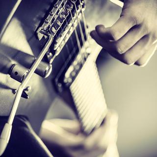 Gros plan sur la main d'une personne qui joue de la guitare. [Fotolia - Voyagerix]