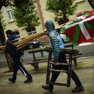 Une personne porte des tréteaux et des drapeaux basques, à Hernani dans le nord de l'Espagne. [Keystone - Alvaro Barrientos]