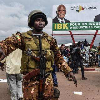Un soldat malien devant un poster de campagne du président sortant Ibrahim Boubacar Keïta. [AFP - Issouf Sanogo]