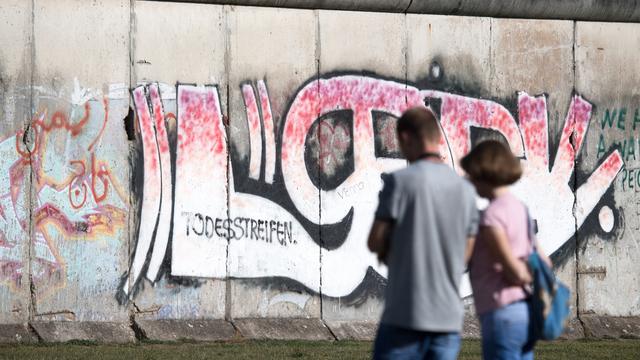 Des touristes devant une section conservée du mur de Berlin, le 13 août 2018. [DPA/Keystone - Ralf Hirschberger]