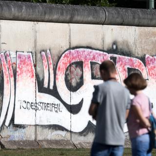 Des touristes devant une section conservée du mur de Berlin, le 13 août 2018. [DPA/Keystone - Ralf Hirschberger]