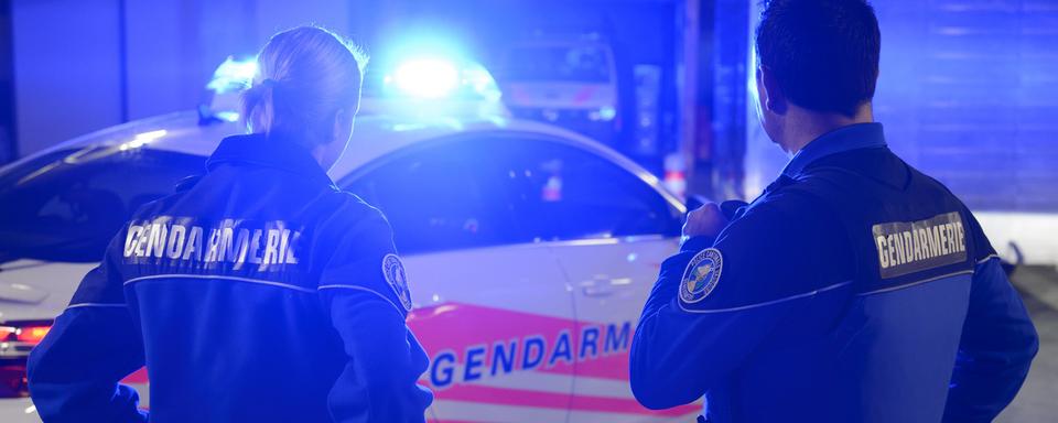 Deux gendarmes vaudois devant leur voiture de patrouille. [Keystone - Laurent Gilliéron]