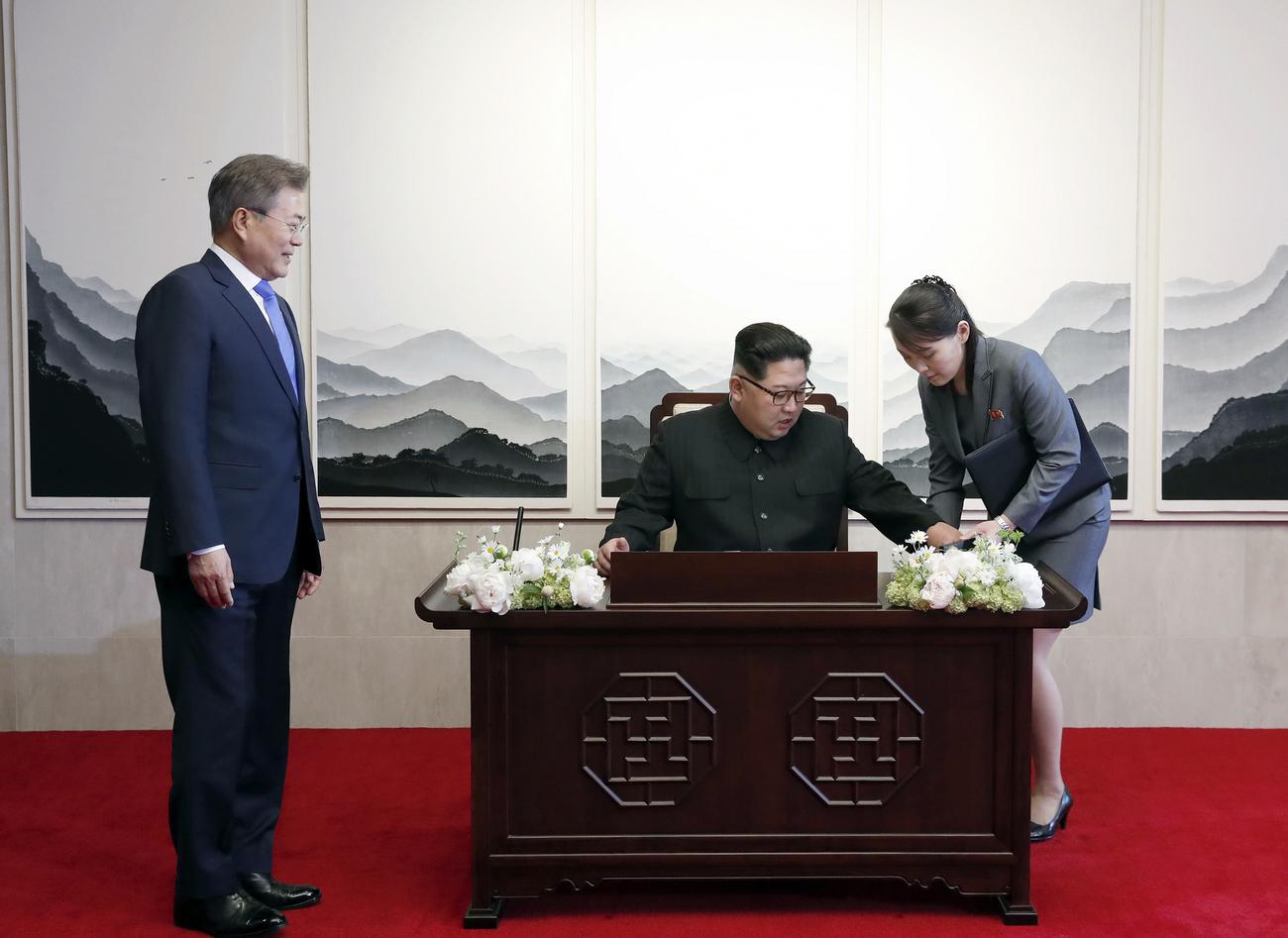 Kim Jong-un s'apprête à signer le livre d'or de la Maison de la paix à Panmunjom. Sa soeur, Kim Yo-jong, lui présente un stylo. [Korea Summit Press Pool via AP]