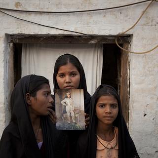 Les filles d'Asia Bibi, cette mère de famille pakistanaise, chrétienne, condamnée à mort pour blasphème, finalement acquittée, posent avec une photo de leur mère, devant leur maison à Sheikhupura au Pakistan, en 2010. [Adrees Latif]