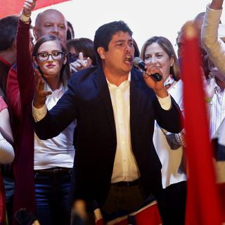 Le vainqueur de la présidentielle Carlos Alvarado, entouré de drapeau aux couleurs du Parti action citoyenne (PAC), donnant son discours à San José. [AP/Keystone - Arnulfo Franco]