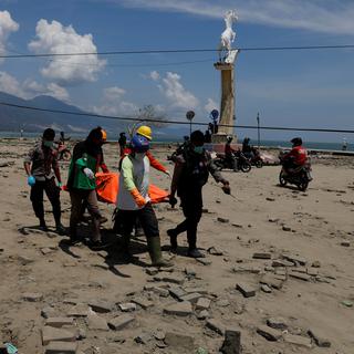 Les membres d'une équipe de secours transportent une victime du séisme qui a frappé l'île indonésienne des Célèbes. [Beawiharta]