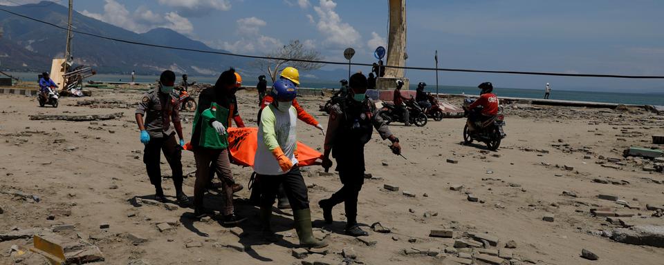 Les membres d'une équipe de secours transportent une victime du séisme qui a frappé l'île indonésienne des Célèbes. [Beawiharta]