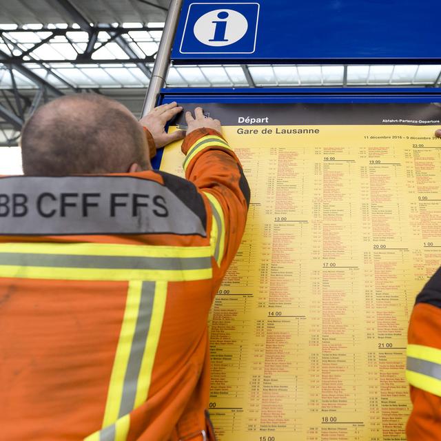 Des employés des CFF changent les affiches horaire à Lausanne (image d'archives). [Keystone - Cyril Zingaro]