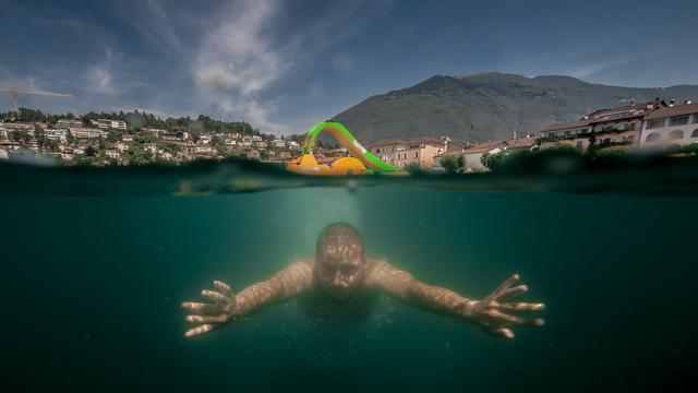 Un homme nage dans le lac Majeur à Ascona. [Keystone - Pablo Gianinazzi]