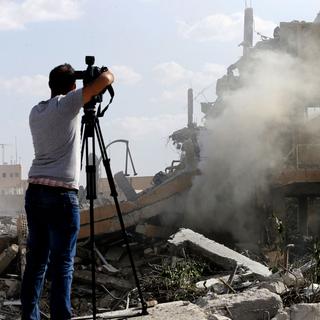 Un journaliste filme la destruction d'un immeuble au nord de Damas. [AFP - Louai Beshara]