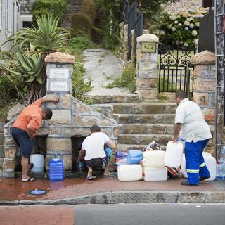 People collect drinking water from pipes fed by an underground spring, in St. James, about 25km from the city centre, on January 19, 2018, in Cape Town. Cape Town will next month slash its individual daily water consumption limit by 40 percent to 50 litres, the mayor said on January 18, as the city battles its worst drought in a century.
RODGER BOSCH / AFP [AFP - Rodger Bosch]