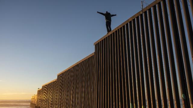 Mardi 11 décembre: un migrant hondurien sur le mur séparant le Mexique des Etats-Unis. [afp - Guillermo Arias]